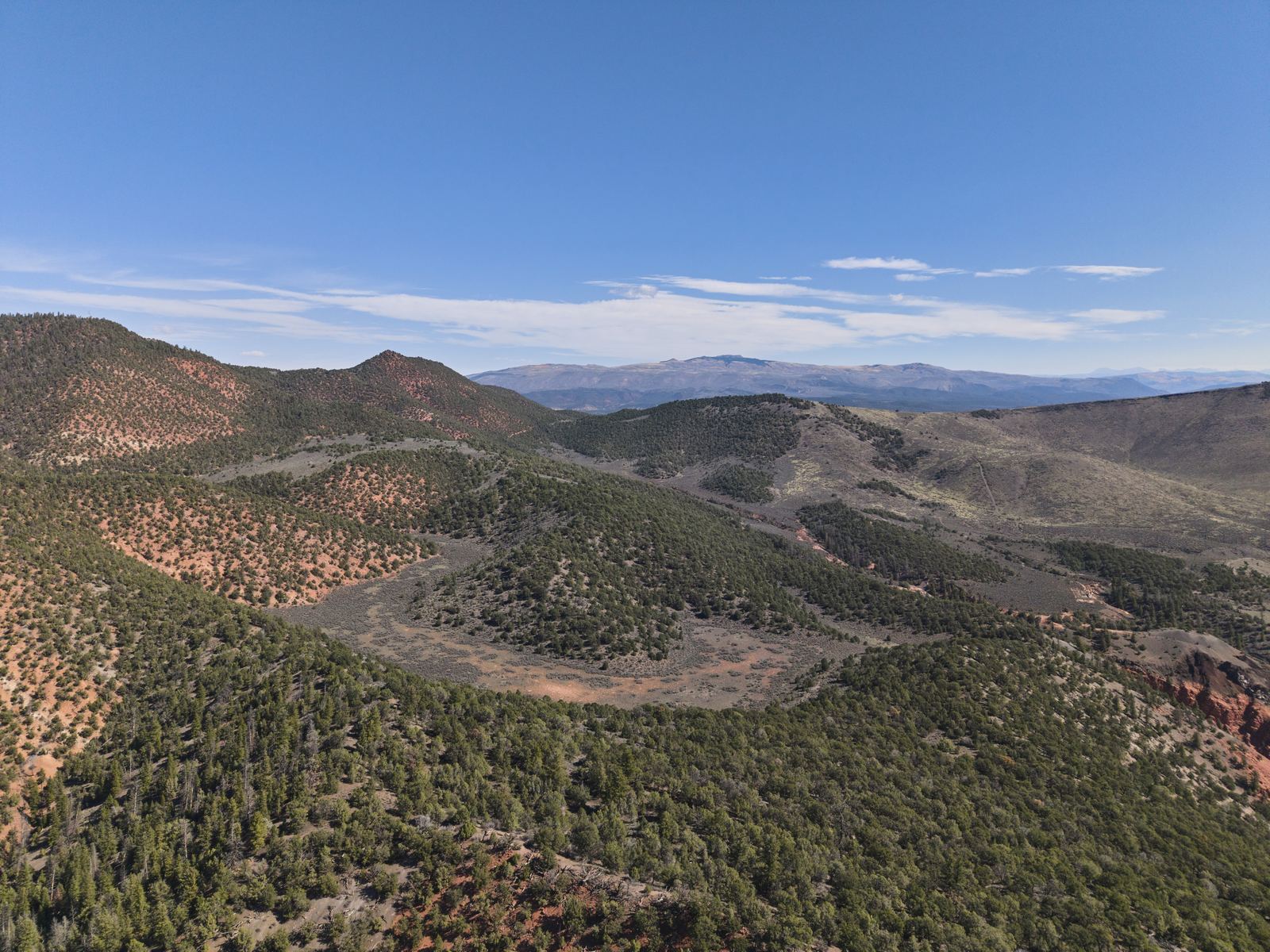 Aerial view over Dotsero Crater, Colorado's only active volcano, a sage-floored bowl ringed by juniper hills west of Gypsum