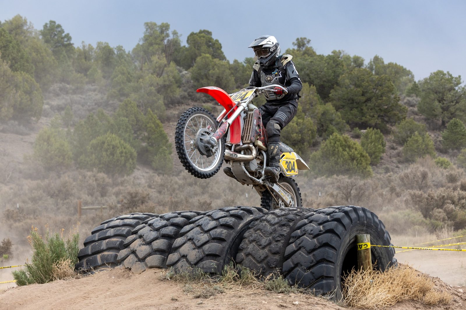 A rider lofting the front wheel over a wall of stacked tractor tires in the endurocross area at Dry Lake