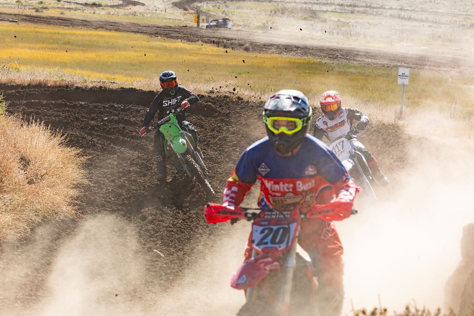 Three riders carving a dusty berm during practice at Dry Lake Motocross Park in Gypsum, Colorado