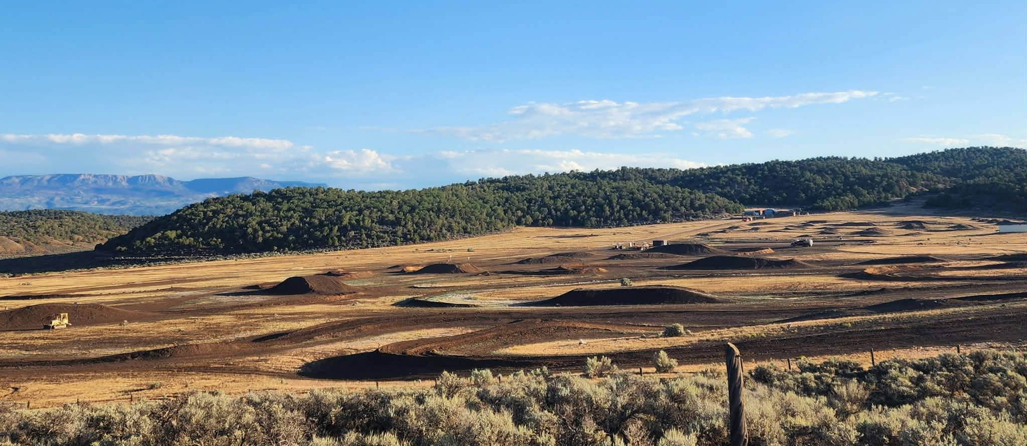 Freshly prepped and watered motocross tracks at Dry Lake Motocross Park in Gypsum, Colorado, spread across open sage country with mountains beyond