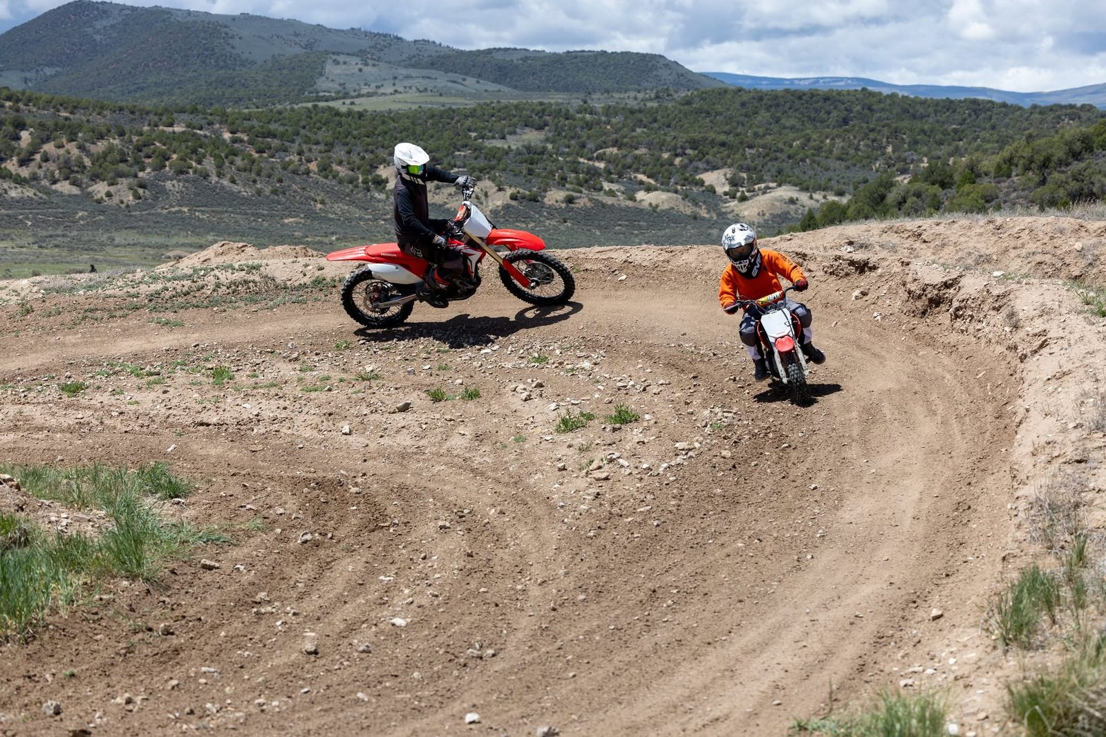 Two young riders on small dirt bikes rounding a berm on a beginner track at Dry Lake