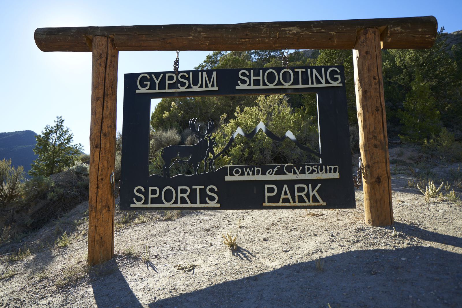The log and steel entrance sign at the Town of Gypsum Shooting Sports Park, cut with a mule deer buck and mountain skyline