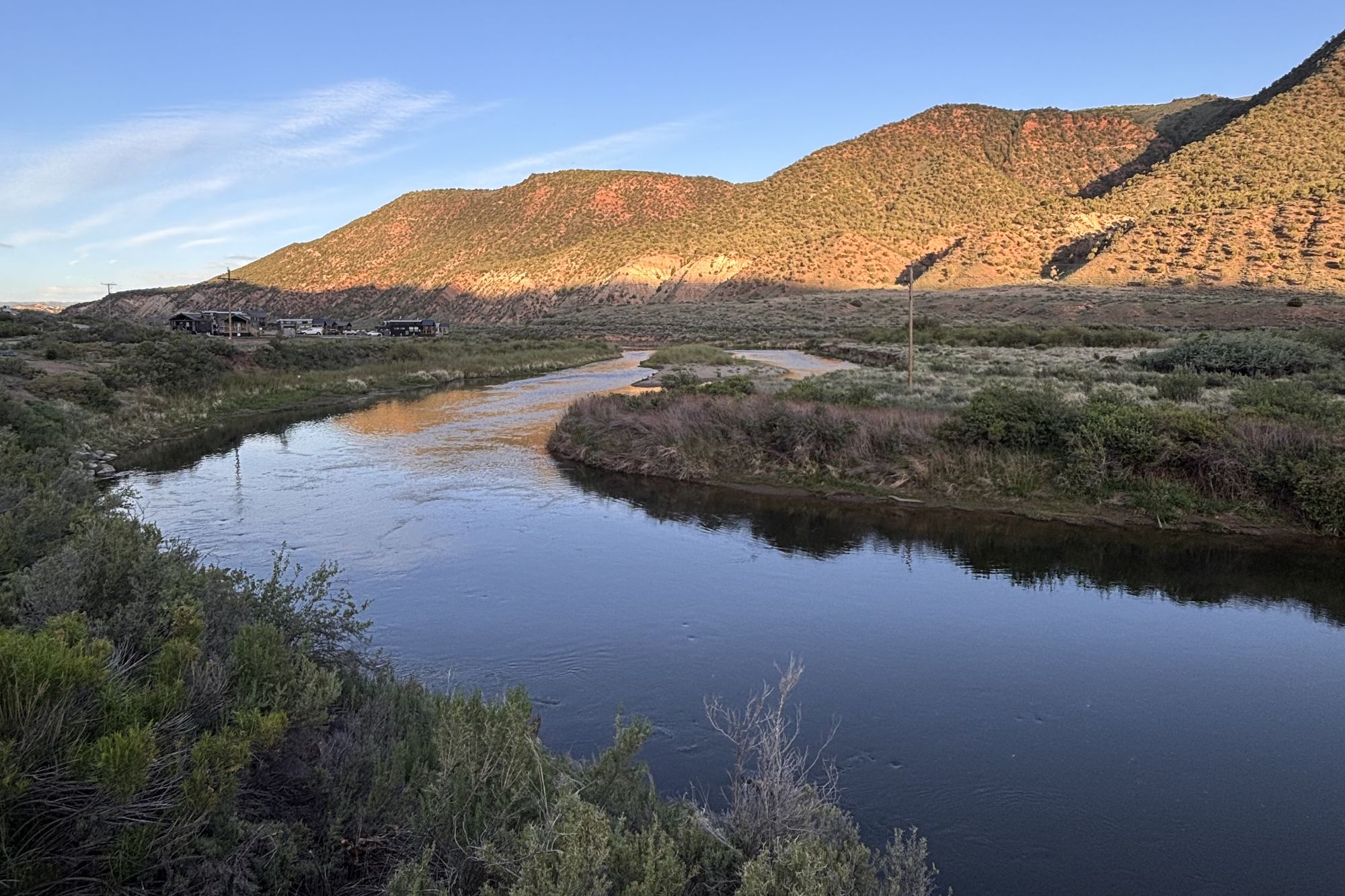 The lower Eagle River bending through sage flats downstream from Gypsum at sunset, with the last light turning the juniper hills red