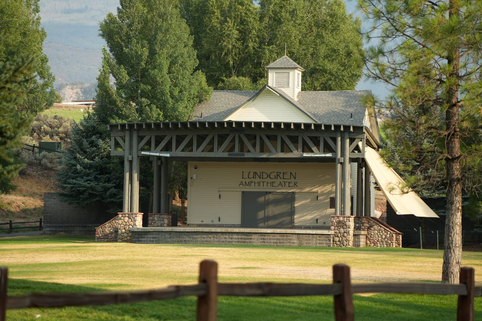 The timber stage of the Lundgren Amphitheater in Gypsum, Colorado, above an empty lawn on a summer evening