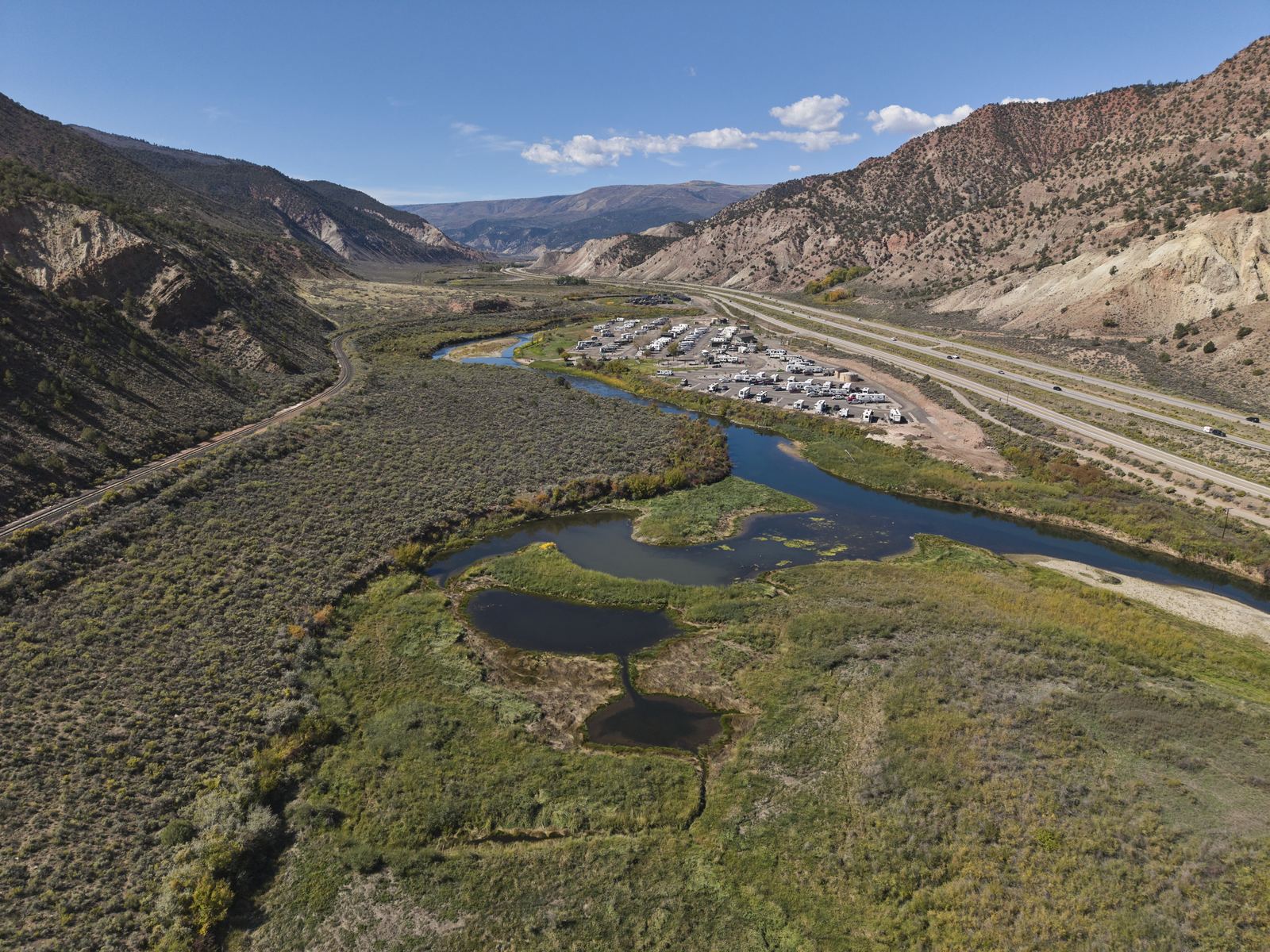 Aerial view of Riverdance RV Resort on the lower Eagle River west of Gypsum, rows of RVs between the river and I-70 with red and white hills on both sides