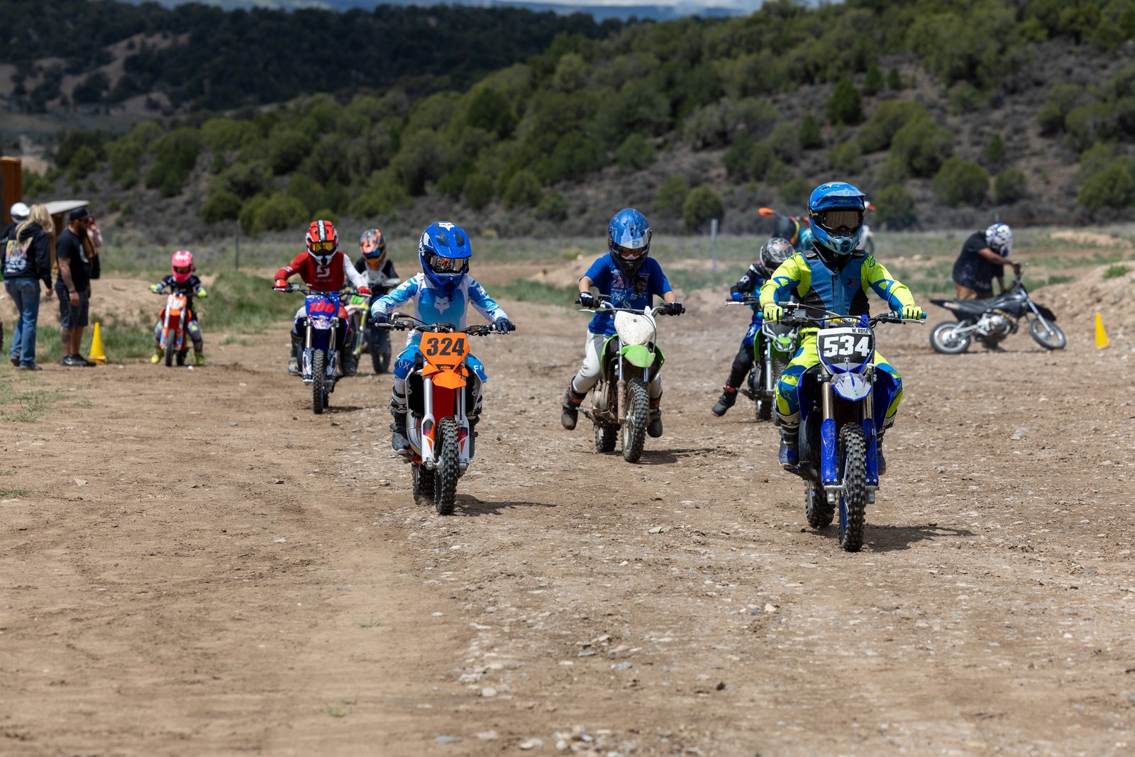 A group of kids on dirt bikes riding together on a dirt track during Take A Kid Dirt Biking Day at Dry Lake
