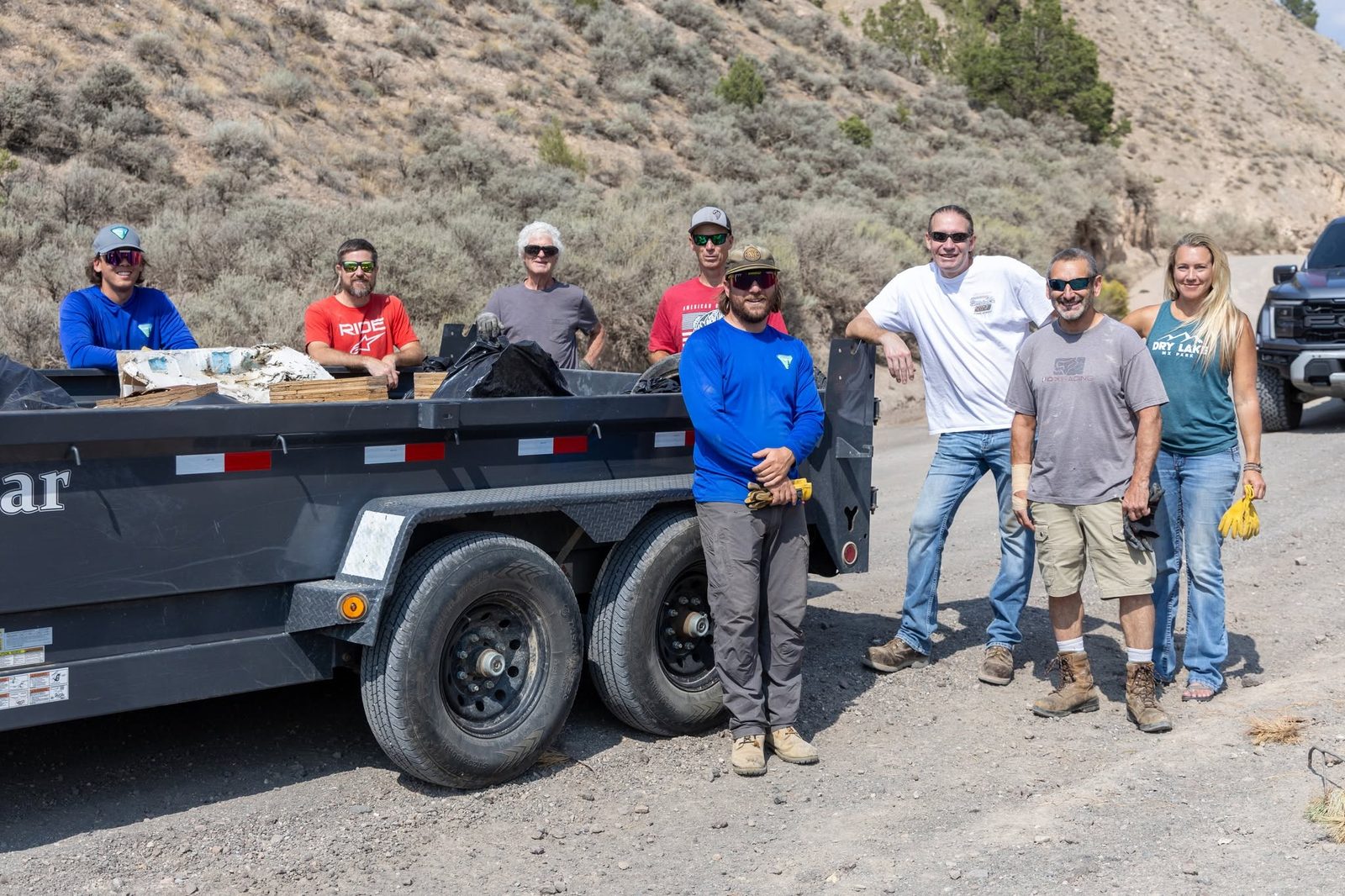 RMSR volunteers and BLM staff standing beside a trailer loaded with trash after a Trail Gulch Road cleanup